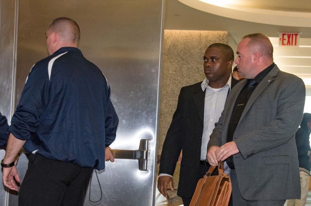 Wayne Isaacs, center, walks through a courthouse hallway flanked by security guards in 2016.
